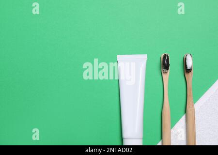 Zahnpasta, Bürsten und Handtuch auf grünem Hintergrund, flach verlegt. Platz für Text Stockfoto