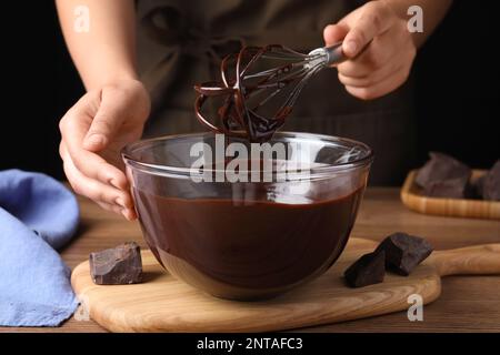 Eine Frau, die köstliche Schokoladencreme am Holztisch macht, Nahaufnahme Stockfoto