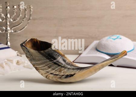 Shofar, Torah und Kippah mit Davidstern auf einem weißen Holztisch. Rosh Hashana Feiertagssymbole Stockfoto