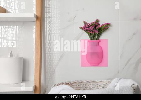 Silikonvase mit Blumen an weißen Marmorwänden im Badezimmer Stockfoto