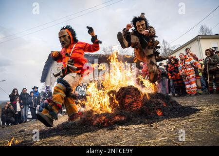 Vila Boa De Ousilhao, Portugal. 21. Februar 2023. Feierliche in Teufelskleidern, die während der Karnevalsfeier in Vila Boa de Ousilhao auf ein Lagerfeuer springen sehen. Vila Boa de Ousilhao ist ein kleines Dorf, das im Tras-os-Montes-Gebirge (im Norden Portugals) verloren ist und die alte Tradition des Karnevals (Entrudo) bewahrt. Feierliche trugen Teufelsmasken aus Holz und durchstreifen das Dorf auf der Suche nach Spaß. (Foto: Hugo Amaral/SOPA Images/Sipa USA) Guthaben: SIPA USA/Alamy Live News Stockfoto