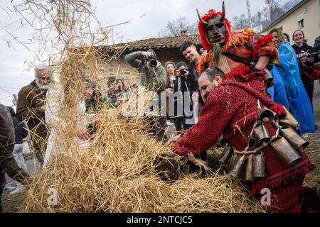 Vila Boa De Ousilhao, Portugal. 21. Februar 2023. Feierliche, als Teufel verkleidete Menschen, die während der Karnevalsfeier in Vila Boa de Ousilhao Spaß in einem Haufen Strohhalme hatten. Vila Boa de Ousilhao ist ein kleines Dorf, das im Tras-os-Montes-Gebirge (im Norden Portugals) verloren ist und die alte Tradition des Karnevals (Entrudo) bewahrt. Feierliche trugen Teufelsmasken aus Holz und durchstreifen das Dorf auf der Suche nach Spaß. Kredit: SOPA Images Limited/Alamy Live News Stockfoto