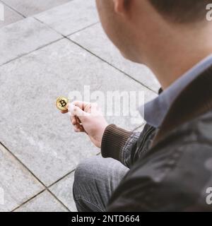 Unerkennbarer junger Mann, der Bitcoin in der Hand hält, Kryptowährungs-Hype-Konzept Stockfoto