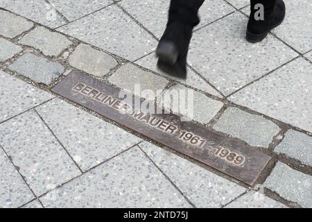 Fußgängerwanderung über Gedenkplakette mit deutschem Text: Berliner Mauer (übersetzt Berliner Mauer) 1961 - 1989 Stockfoto