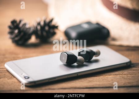 Ein Paar schwarze, echte schnurlose Ohrstöpsel mit Smartphone. Entspannungskonzept. Stockfoto