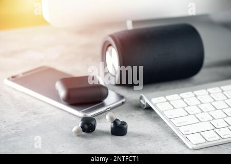 Ein Paar schwarze, echte schnurlose Ohrstöpsel mit Smartphone. Entspannungskonzept. Stockfoto