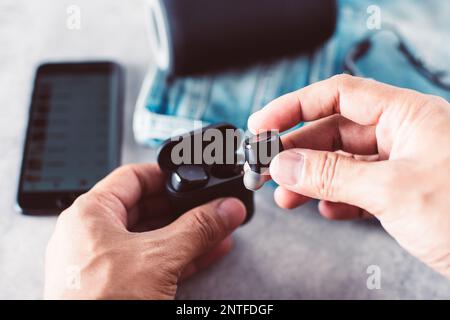 Ein Paar schwarze, echte schnurlose Ohrstöpsel mit Smartphone. Entspannungskonzept. Stockfoto