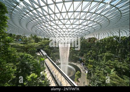 Blick auf den Regenvortex am Flughafen Jewel Changi vom Canopy Park, der sich auf der obersten Ebene (L5) befindet, und dem Terminal Shuttle-Zug, der am Wasserfall vorbeifährt Stockfoto
