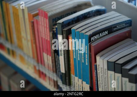 Bücher sind ordentlich aus nächster Nähe angeordnet, auf Einem eisernen Regal der Bibliothek Stockfoto