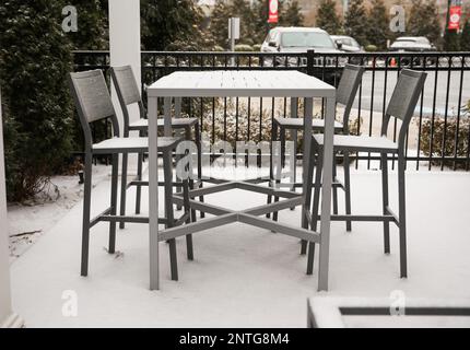 Schnee auf Bänken, Tischen und Stühlen im Freien im Winter, bedeckt von weißem Schneefall während des Sturms in der Stadt Providence Stockfoto