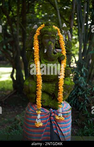 Dieses Foto zeigt eine atemberaubende Statue einer Gottheit mit dem Kopf eines Elefanten, bedeckt mit einem üppigen Mantel aus grünem Moos. Die komplizierten Details der Sta Stockfoto