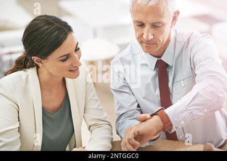 Er ist ein Geschäftsmann mit Verbindungen. Ein Geschäftsmann zeigt einem Kollegen seine intelligente Uhr. Stockfoto
