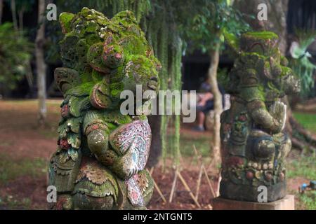 Atemberaubende Statue einer Gottheit mit dem Kopf eines Elefanten, bedeckt mit einem üppigen Mantel aus grünem Moos. Die komplexen Details der Statue sind sichtbar Stockfoto