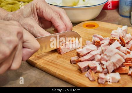 Der Koch schneidet Speck in der Küche für das Rezept Stockfoto