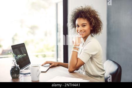 Ich habe mein eigenes Unternehmen gegründet und es boomt. Abgeschnittenes Porträt einer attraktiven jungen Geschäftsfrau, die zu Hause an ihrem Laptop arbeitet. Stockfoto