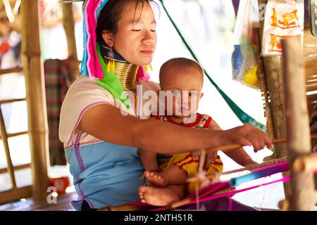 Eine Frau vom Langhals-Stamm, bekannt für die Metallringe um ihren Hals, die ihr Kind halten. Das Foto zeigt die Verbindung zwischen Mutter und Chi Stockfoto