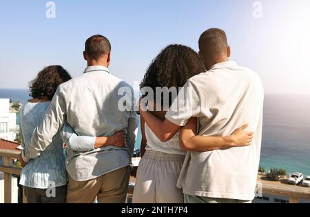 Umarmung, Liebe und Familie mit Blick auf das Meer während eines Urlaubs, Freiheit und Verbindung in Bali. Zuneigung, Urlaub und Rücken von Eltern und Paar auf einer Stockfoto