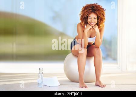Hol dir ein Ganzkörper-Workout mit einem Fitnessball. Eine sportliche junge Frau, die auf einem schweizer Ball sitzt. Stockfoto
