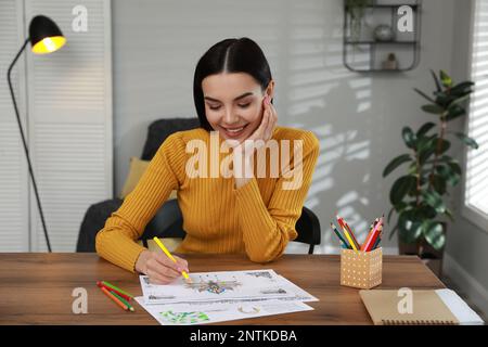 Eine junge Frau, die eine Anti-Stress-Seite am Tisch drinnen ausmalen kann Stockfoto