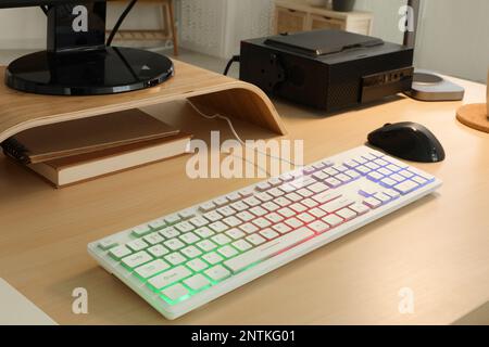 Moderne RGB-Tastatur und Maus auf Holztisch im Innenbereich Stockfoto