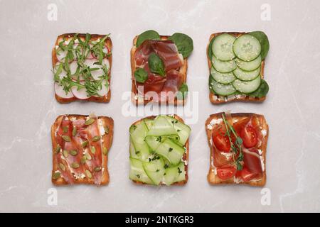 Verschiedene leckere Sandwiches auf hellgrauem Marmortisch, flach liegend Stockfoto