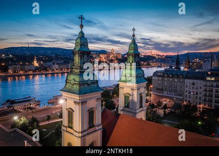 Budapest, Ungarn - aus der Vogelperspektive auf die beleuchtete Innenstadtkirche der Himmelfahrt in der Dämmerung von Budapest mit dem königlichen Palast von Buda Stockfoto