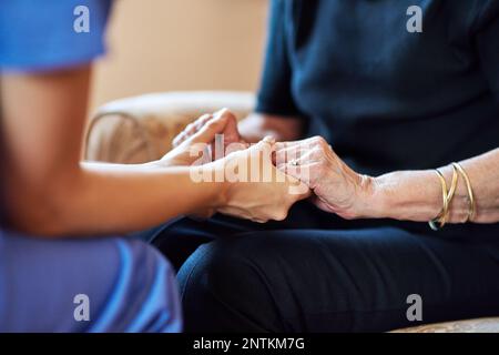 Sie ist da, wenn du sie brauchst. Eine Krankenschwester, die eine ältere Frau mitfühlend an den Händen hält. Stockfoto