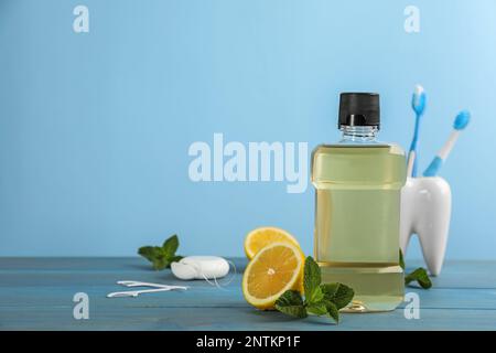 Mundspülung und andere Mundpflegeprodukte auf hellblauem Holztisch, Platz für Text Stockfoto