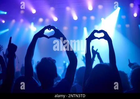 Ihre Liebe zu zeigen. Aufnahme von anbetenden Fans bei einem Rockkonzert. Stockfoto