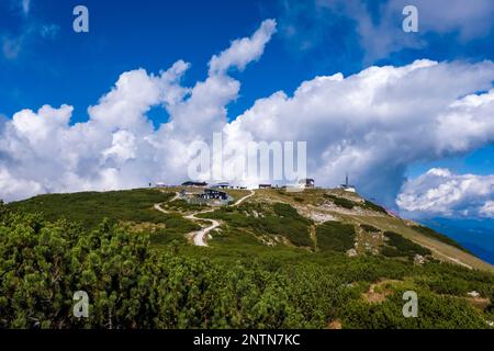 Gebäude und Seilbahnstation auf dem Gipfel des Cima Paganella Berges, hinter dem sich Sturmwolken bilden. Stockfoto