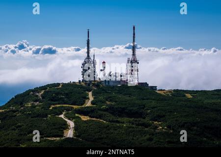 Telekommunikationsstation auf dem Gipfel des Berges Cima Paganella, das Tal unter Wolken. Stockfoto