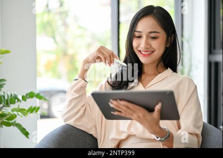 Charmante und attraktive asiatische Millennials-Geschäftsfrau oder Unternehmerin, die ein digitales Tablet verwendet und auf der Suche nach Inspiration im Internet ist. Stockfoto