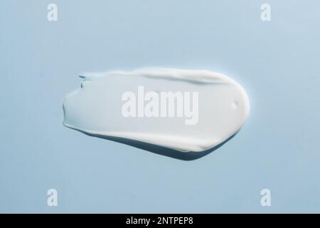 Weiße cremefarbene Konsistenz, Hautpflegelotion auf Blau. Gesichtscreme, Körperpflegemittel, Haarspülmittel verschmieren den Farbhintergrund. Stockfoto
