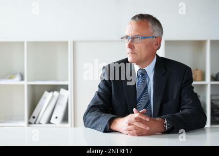 Die nächste Bewegung seiner Gefährten in Erwägung ziehen. Aufnahme eines älteren Geschäftsmannes, der an einem Tisch sitzt. Stockfoto