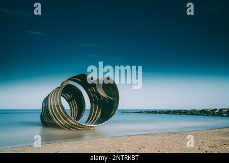 Metall St. Mary's Muschel im Wasser am Strand. Künstlerische Struktur am Cleavleys Beach Stockfoto