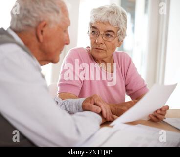 Sich Zeit nehmen, um wichtige Angelegenheiten zu besprechen. Aufnahme von zwei älteren Menschen, die ein Dokument diskutieren. Stockfoto