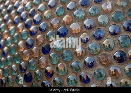 Nahaufnahme des Mosaikhintergrundes von runden glasblauen türkisfarbenen Kugeln in der Wand Stockfoto