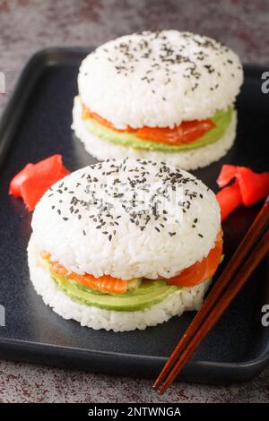 Sushi-Burger mit Avocado und Lachs auf dunklem Hintergrund. Selektiver Fokus. Vertikal Stockfoto