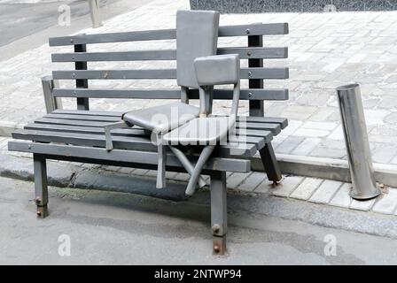 Die Skulpturenstühle auf der Bank befinden sich in der Kiew Passage Street, gleich neben der Hauptstraße der Stadt Khreshchatyk in Kiew, Ukraine Stockfoto