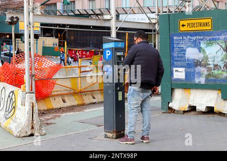 Eine Person, die eine Parkuhr in NYC verwendet. Das Münzmessgerät druckt einen Zahlungsbeleg. Stockfoto