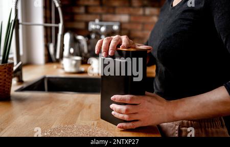 Ein Mädchen öffnet in der Küche einen Tee-Metallbehälter Stockfoto