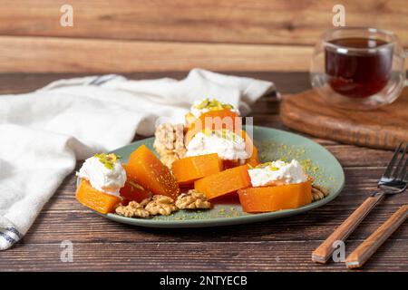 Cremiges Kürbis-Dessert. Süße türkische Ramadan-Delikatessen. Kürbis-Dessert mit Sorbet auf grauem Hintergrund. Stockfoto