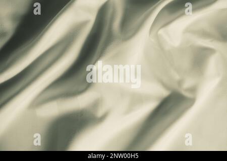 Zerknittertes Material aus Satin in heller Olivfarbe, Draufsicht. Natürliche Bettwäsche, Laken, abstrakter Hintergrund aus luxuriösem Stoff, wellenförmige Falten Stockfoto