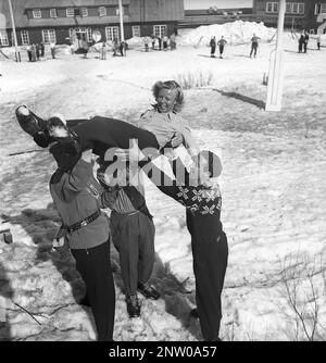 In den schneebedeckten Bergen 1940er. Olga Sjögren aus Stockholm ist in der typischen Wintersportmode aus dem Jahr 1940er gekleidet, die von drei Männern, die ihre Leistung feiern, in die Luft geworfen wird. Sie klettert auf den Berg Kuoblatjåkko in Norrbotten Schweden. Der letzte von sieben Bergen, die sie erklommen hat, um die Auszeichnung zu erhalten: Die sieben Gipfel. Sie verbrachte 60 Stunden und stieg insgesamt 6558 Meter hoch, nachdem sie fertig war. Schweden 1943 Kristoffersson Ref H138-2 Stockfoto