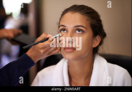 Umarbeitung. Aufnahme einer attraktiven jungen Frau, die sich im Gesicht schminken ließ. Stockfoto