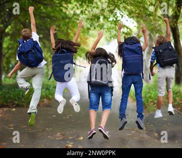 Frühlingsferien. Rückansicht aufgeregt Schüler springen in einer Reihe. Stockfoto