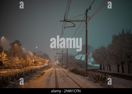 Schneebedeckte Eisenbahnstrecke oder Eisenbahnstrecke, die nachts mit Schnee bedeckt ist. Stockfoto