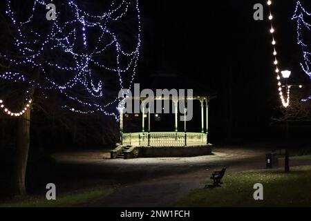 Ein Bühnenstand in einem englischen Stadtpark, der nachts beleuchtet und von Lichtern beleuchtet wird Stockfoto