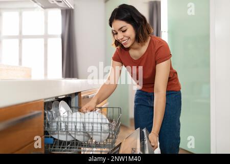Wunderschöne Junge Araberin, Die Geschirrspülmaschine In Die Küche Zu Hause Lädt Stockfoto