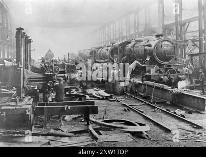 Dampflokomotiven-Reparaturwerkstatt Kobe Japan. Ein Innenraum, in dem mehrere Lokomotiven hintereinander zu sehen sind, an denen Mechaniker arbeiten. 1930er Stockfoto